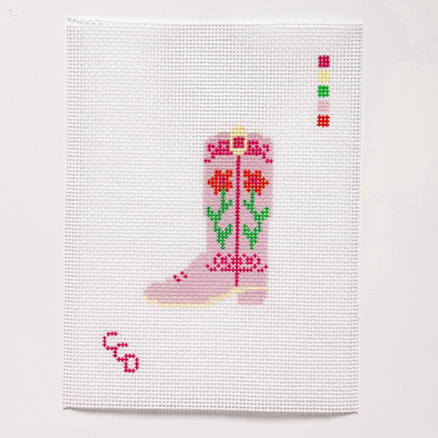 Needlepoint pink boot with floral design on a white fabric background
