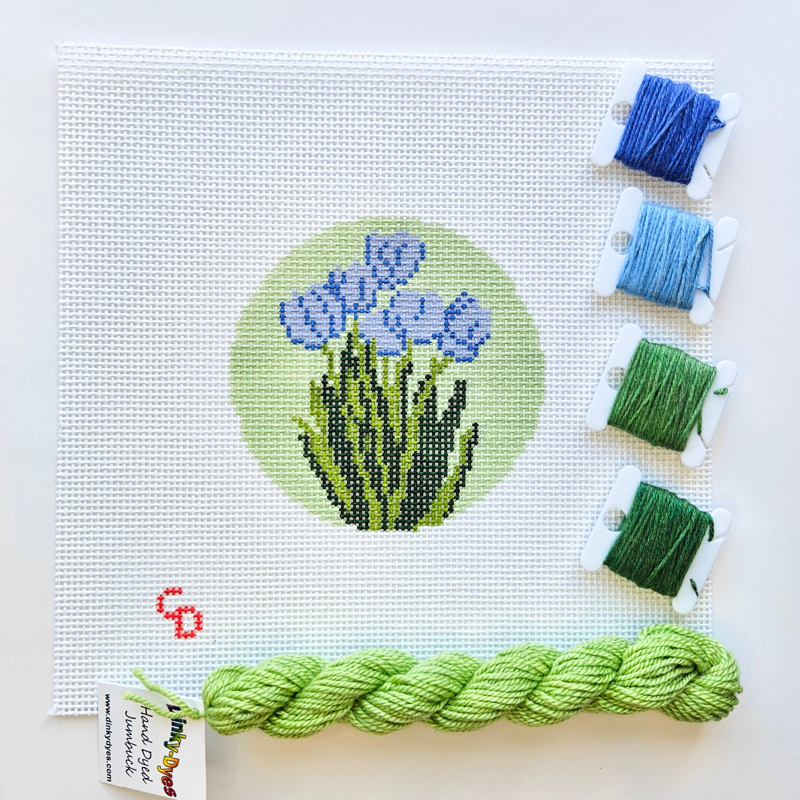 Needlepoint kit with blue and green threads on a white background