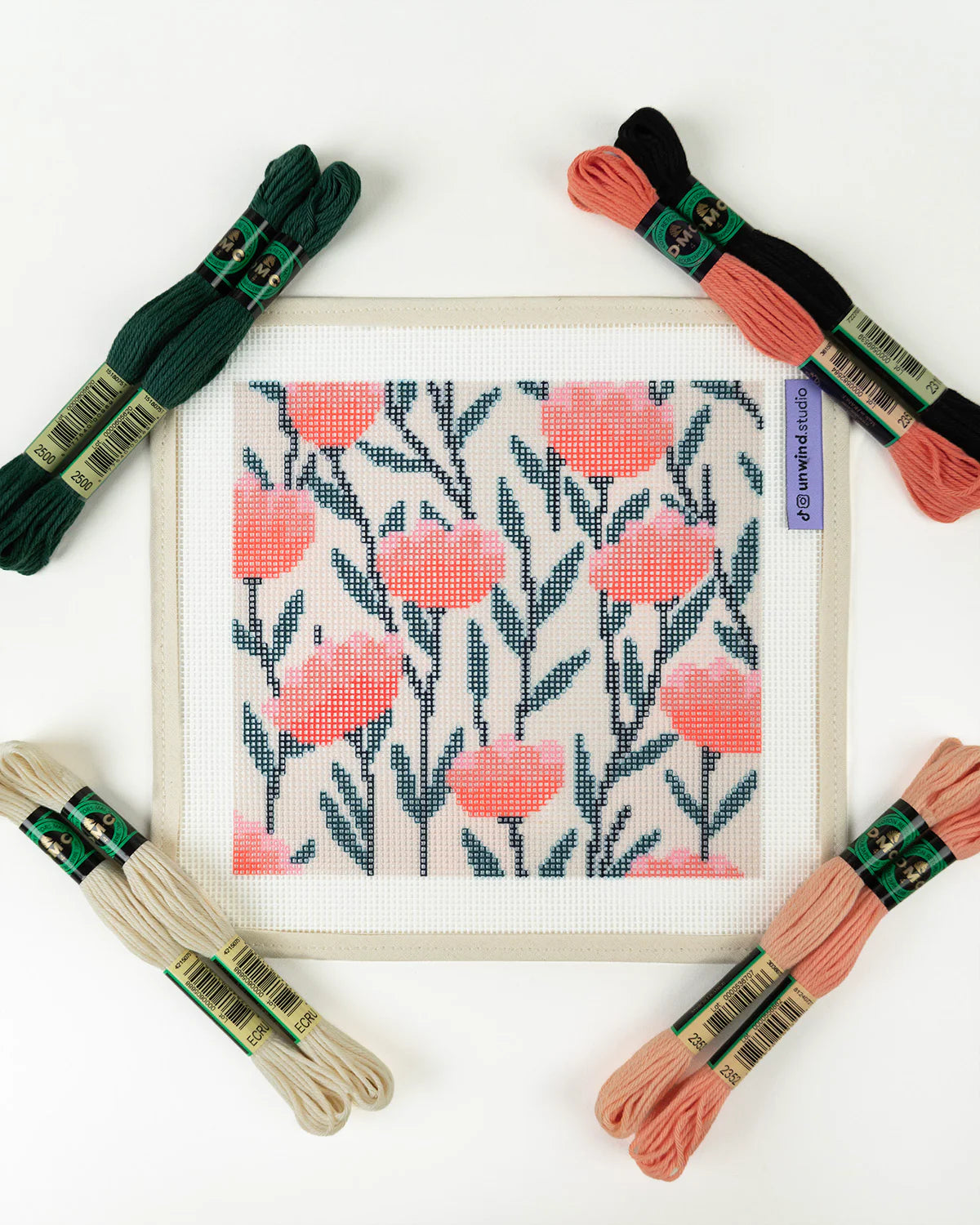 Needlepoint floral pattern with embroidery threads on a white background
Details