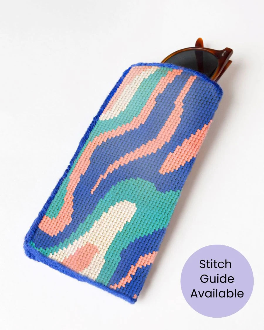 Colorful needlepoint sunglasses case on a white background with 'Stitch Guide Available' text.