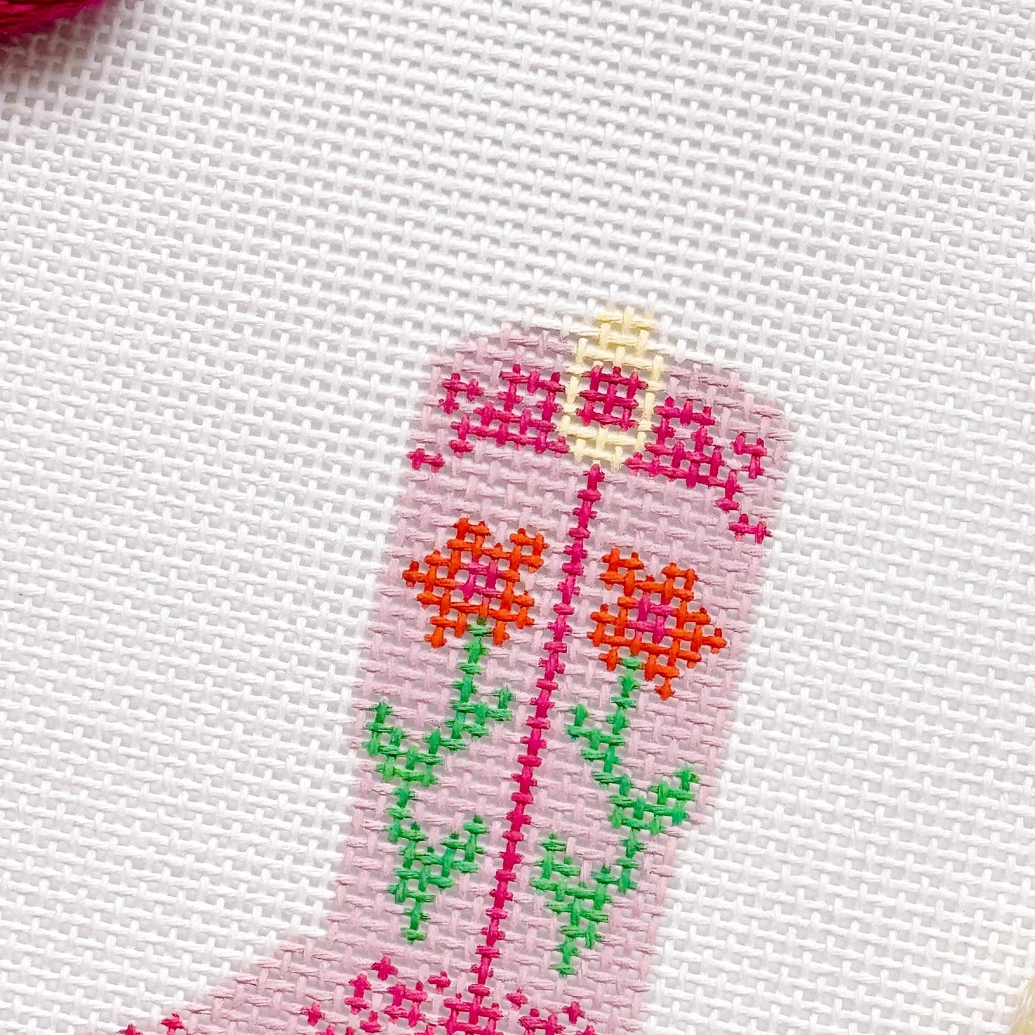 Needlepoint  design on fabric with pink, green, and orange colors.