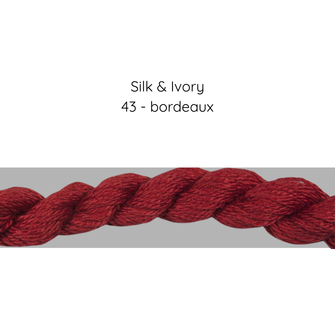 Red yarn skein labeled 'Silk & Ivory 43 - bordeaux' on a gray background