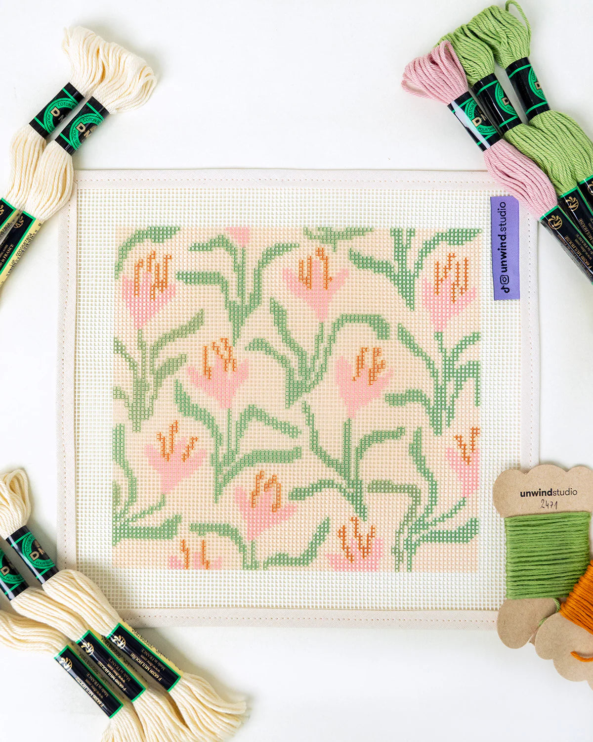 Needlepoint kit with floral pattern and embroidery threads on a white background