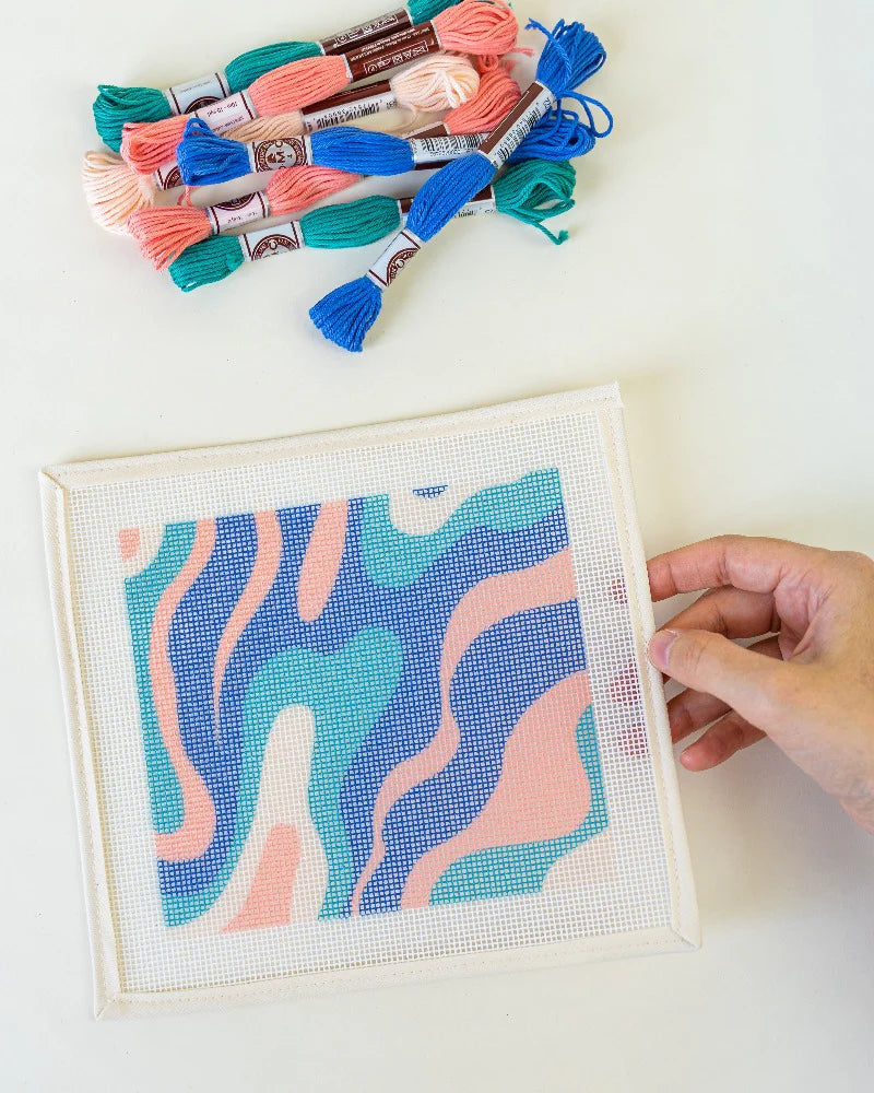 Needlepoint project with colorful thread skeins on a white background